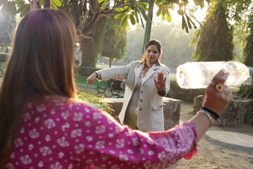 Woman telling young girl, not to throw garbage or plastic trash in park or public place to keep environment clean. Swachh Bharat Abhiyan. Clean India. natural peaceful environment.