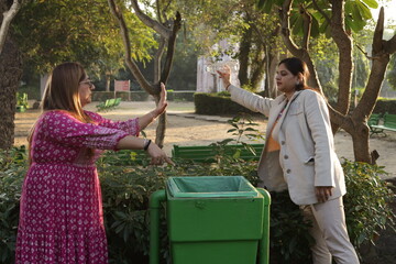 Woman telling young girl, not to throw garbage or plastic trash in park or public place to keep...