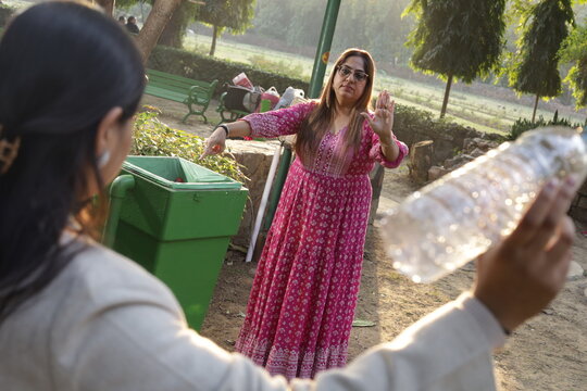 Woman telling young girl, not to throw garbage or plastic trash in park or public place to keep environment clean. Swachh Bharat Abhiyan. Clean India. natural peaceful environment.