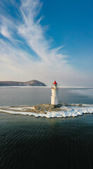 Aerial view of the lighthouse in winter in the ice at dawn