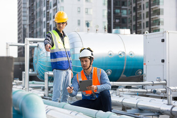 Group of male plumber working and inspecting quality of water pipes system at rooftop of building. Team of Asian male plumber maintenance water pipes network system on building rooftop