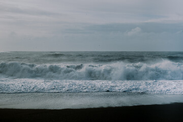 Fototapeta premium Wave sea background on Iceland black sand beach with cloudy sky