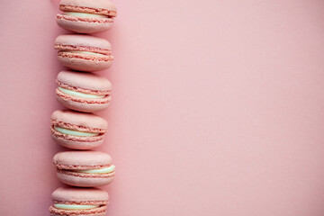 Pink macarons stacked in a vertical line on a pastel background