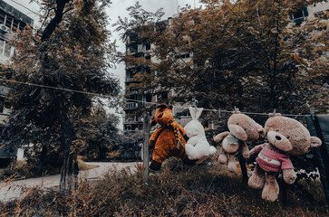 children's toys hang on a rope against the background of destroyed burnt houses in Ukraine