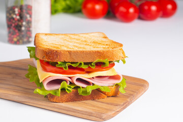 Close-up of two sandwiches with bacon, salami, prosciutto and fresh vegetables on rustic wooden cutting board. Club sandwich concept - 760433052
