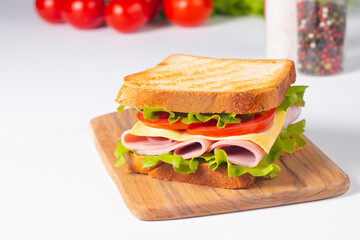 Close-up of two sandwiches with bacon, salami, prosciutto and fresh vegetables on rustic wooden cutting board. Club sandwich concept - 760433069