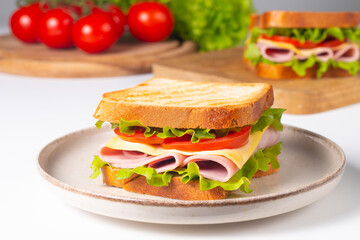 Close-up of two sandwiches with bacon, salami, prosciutto and fresh vegetables on rustic wooden cutting board. Club sandwich concept - 760433071