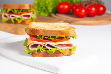 Close-up of two sandwiches with bacon, salami, prosciutto and fresh vegetables on rustic wooden cutting board. Club sandwich concept - 760433082