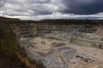 Sandstone quarry with excavator equipment under dramatic sky.. Digging industry background, Czech landscape