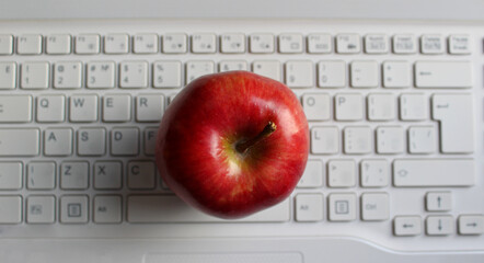 Apple Of Knowledge Concept. Perfect Ripe Apple Fruit On White Defocused Laptop Keyboard Top View
