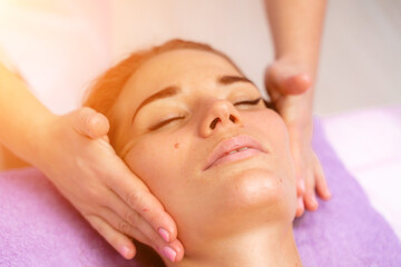 Relaxing massage. European woman getting facial massage in spa salon, side view