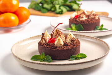 Delicious chocolate tart garnish with cherry and mint. Classic dessert. - 760444642