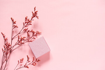 Flat lay of pink gift box with a branch of dry pink flowers on the light pink background. Women's...