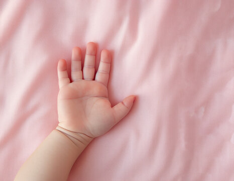 white baby hand on pink blanket top view with copy space