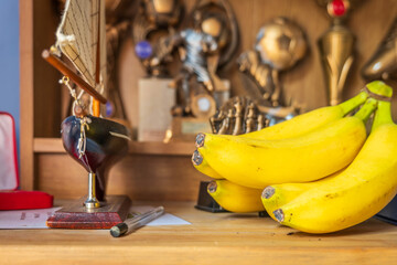 Fototapeta na wymiar Fresh ripe banana fruit on bedroom shelf with sport award on background
