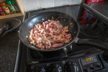 Frying chicken fillet slices with onion in frying pan