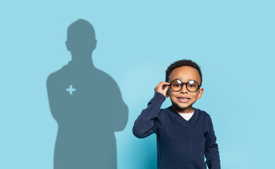 A confident young boy with glasses adjusts his frames, smiling against a blue background