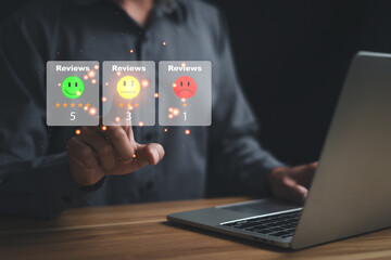 A man is pointing face a laptop with a screen displaying three smiley faces