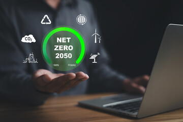 Businessman is holding with laptop and a green circle on it that says Net Zero 2050