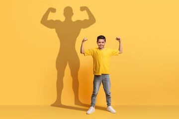 An enthusiastic young boy in a yellow shirt flexes his arms with confidence