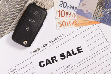 Car key, euro banknotes and vehicle sales agreement. Inscription car sale. Sales and buying new or...