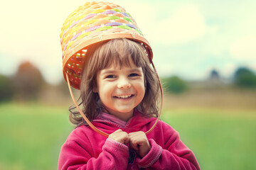 Happy smiling little girl walking through a meadow with a picnic basket on her head - 760473891