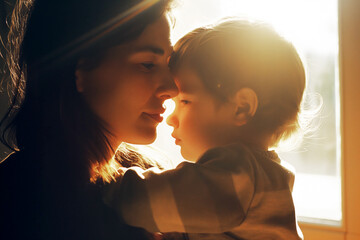 Intimate love scene of a mother and her son in arms at cozy home. Quiet moment of love and pure feelings between mom and child with warm light