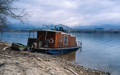 Fototapeta na wymiar Houseboat anchored in the lake in Slovakia, Lipotvska Mara. Old houseboat, retro style living