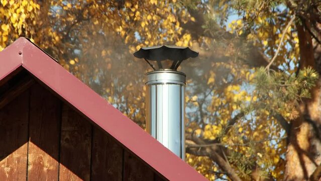 Chimney with smoke close-up against the background of an autumn forest