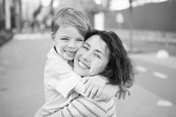 young mother and son smiling looking at the camera in modern residential complex. Having fun together, happy parenting, new home concept. Bright summer day in the urban background. High quality photo