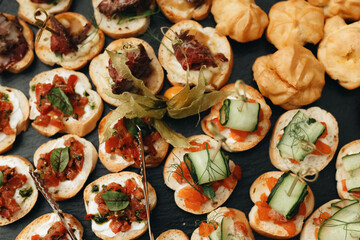 Beautifully decorated catering banquet table with different food snacks and appetizers with sandwich, caviar, fresh fruits on corporate christmas birthday party event or wedding celebration.