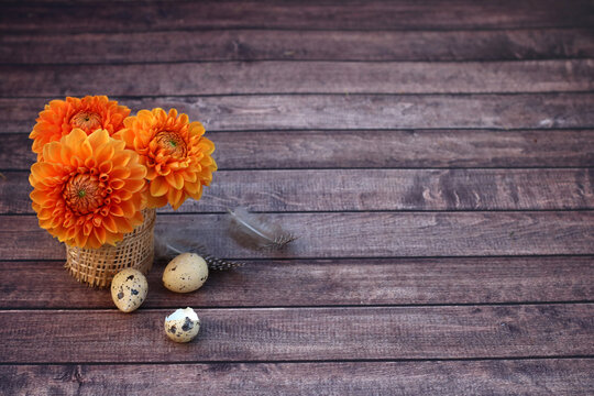 A bouquet of flowers and quail eggs on a rustic wooden board with space for a text.