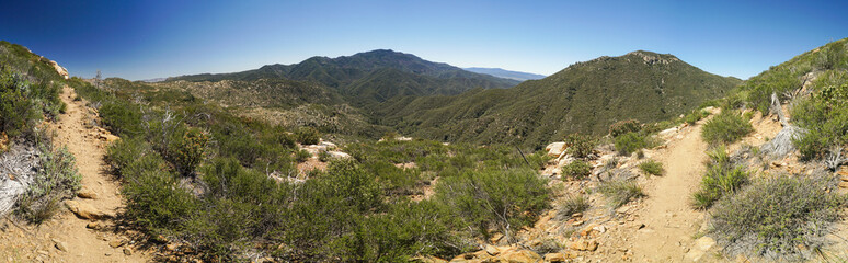 Fototapeta na wymiar A panoramic view of a mountain range with a dirt path leading to the top