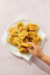 Child holding plate of chicken nuggets a classic comfort food