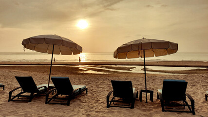 Beach beds under an umbrella on the beach with beautiful sea sunrise time.