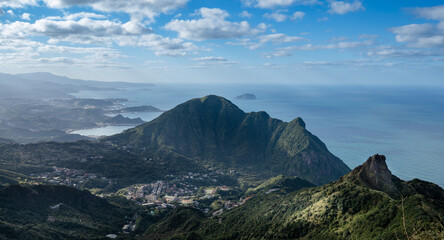 Fototapeta premium Overlooks two peaks in northeast Taiwan, teapot mountain and Keelung mountain, and Keelung island also in the distances of ocean, sunlight shines on the village, in Jiufen, Jinguashi, New Taipei