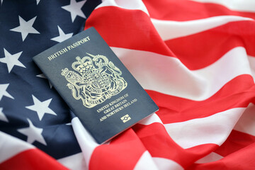 Blue British passport on United States national flag background close up. Tourism and diplomacy concept