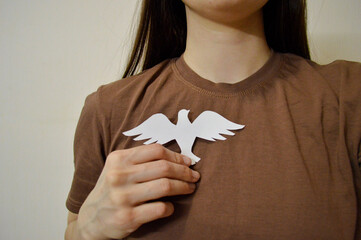 Girl holding paper bird on her chest. Day for the Abolition of Slavery. World Day Against the Death...