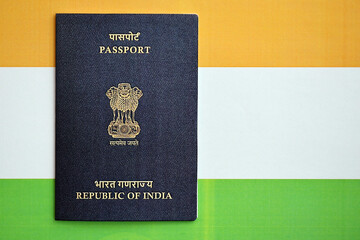 Blue Indian passport on national flag background close up. Tourism and citizenship concept