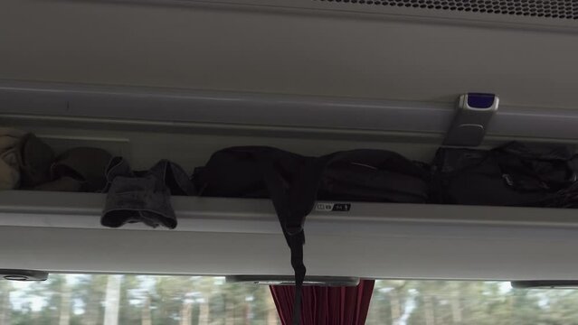 Passengers personal belongings lie untidy on open side shelf of the bus while it is moving. Unsafe luggage compartment for hand luggage attracts thieves and scammers. Unprotected luggage rack.
