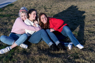Naklejka na ściany i meble Three friends relaxing on grass in sunlight
