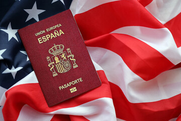 Red Spanish passport of European Union on United States national flag background close up. Tourism and diplomacy concept - obrazy, fototapety, plakaty