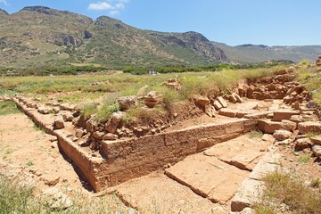 Landscape view of ancient City of Phalasarna archaeological site with stone ruins in sunny spring weather, Falasarna, Crete, Greece.