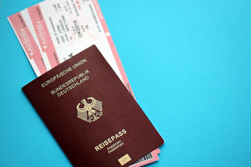 Red German passport of European Union with airline tickets on blue background close up. Tourism and travel concept