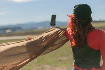 Mujer con pelo rojo y un pañuelo al aire haciéndose fotos 