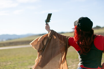 Mujer con pelo rojo y un pañuelo al aire haciéndose fotos 