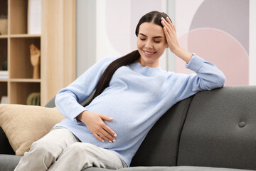 Happy pregnant woman on sofa at home