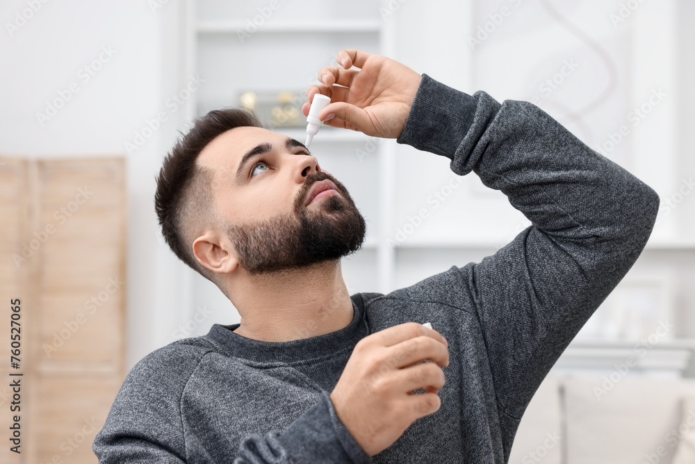 Sticker Young man applying medical eye drops indoors