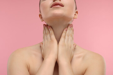 Obraz na płótnie Canvas Woman touching her neck on pink background, closeup