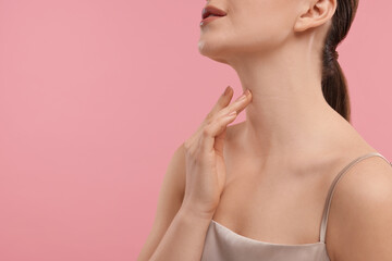 Fototapeta na wymiar Woman touching her neck on pink background, closeup. Space for text